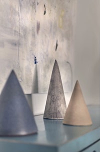 three cones sit on a table next to a painting